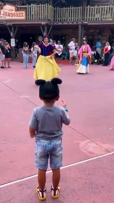 4-year-old boy tips his hat to Disney princesses during parade.