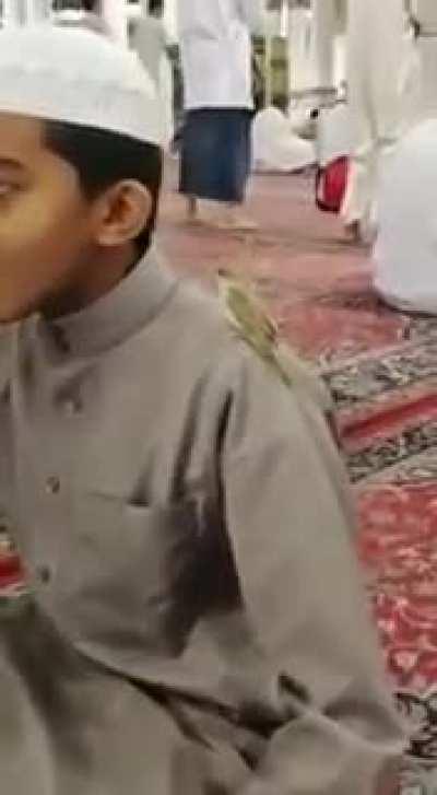 The bird is standing on his shoulder while revising the Quran in the Prophet’s Mosque.