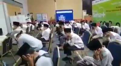 Indonesian Islamic school students closing their ears when music plays in a covid vaccination queue