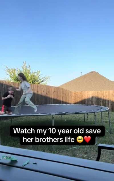 Young girl performs a heimlich maneuver on her younger brother.