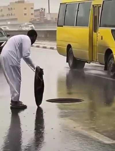 Resetting a manhole cover on a busy highway in the rain
