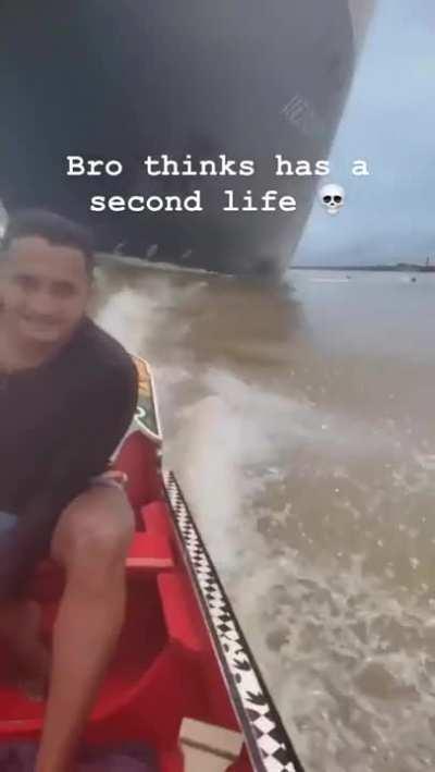 Dude going in a boat under huge ship