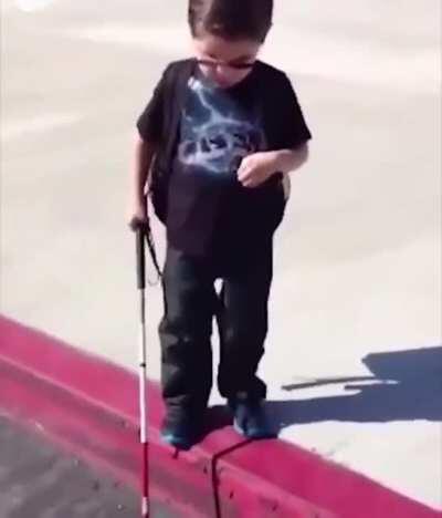 Blind kid experience his first curb by himself while his parents encouraged him.