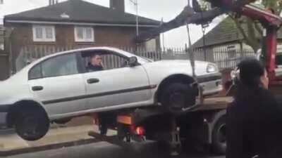 Idiot desperately tries to save car from towing