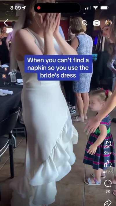 Kid wiping her eyes on brides dress