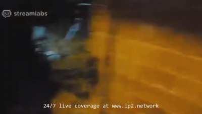 A Muslim man and his pregnant wife look on as looters steal from their phone store.