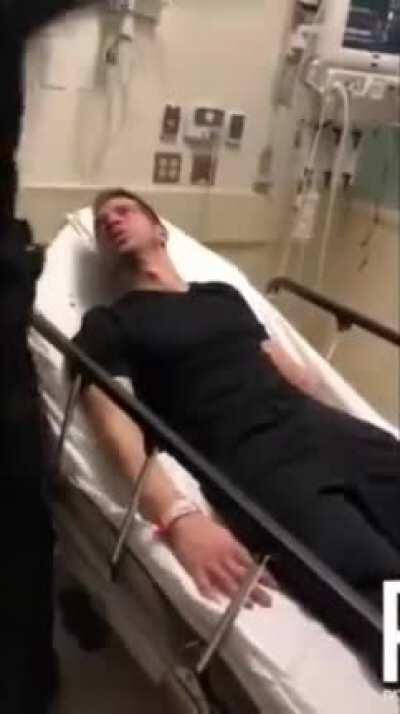 Police beating a man in hopsital bed.