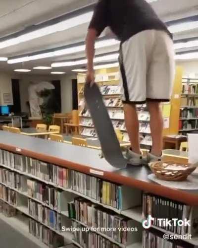 Riding a skateboard ok the bookshelves