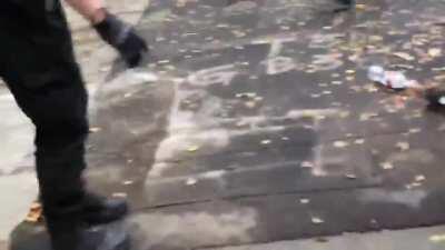 A man is chased into an alley by black-clad people and beaten while screams of 