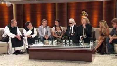 Salma had to be convinced to wear this outfit. Karl Lagerfeld (the guy wearing glasses) convinced her. She was breastfeeding and didn’t want to wear a corset. Immediately the host speaks in German to say a sexual innuendo about her that she doesn’t unders