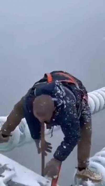 This Chinese worker working to fix a power line during a storm