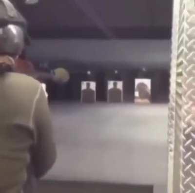 Guy fires RPG at an indoor firing range, with someone behind him