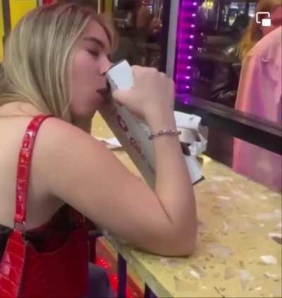 Woman calmly eats a pizza box.