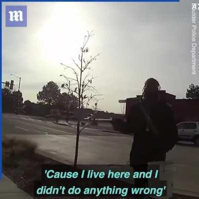 Police officer detaining a man for picking up trash outside of his home.
