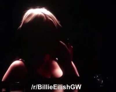 Billie Eilish taking her top of at a live show
