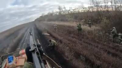 A group of Russian soldiers shoot a hostile FPV drone that was closing in on a friendly car driving past them, one of them keeps aiming an anti-drone gun towards the drone the whole time, South Donetsk front