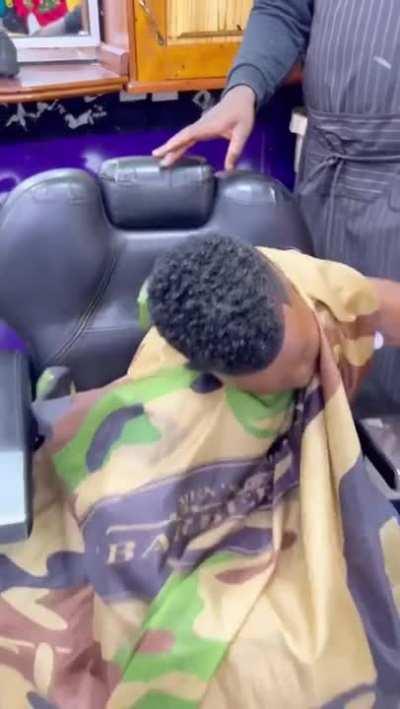Sleeping kid thinks the barber kisses him.