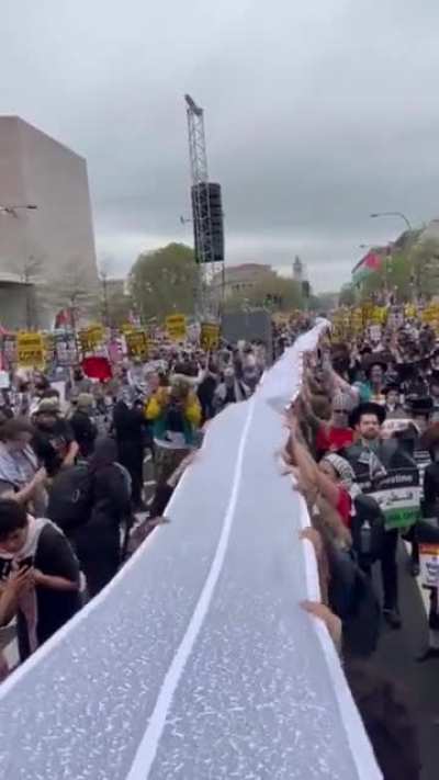 In D.C. today, a massive banner has been unveiled with the names of Palestinians killed by Israel since October 2023.