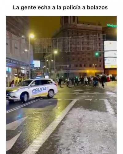 People in Madrid hitting a police car with snowballs when they tried to interrupt a snowball fight