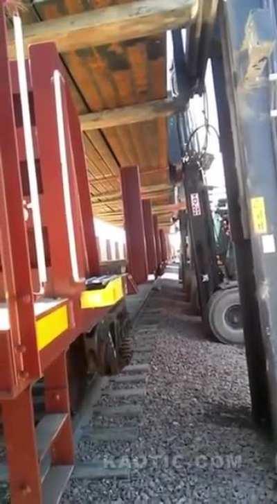 Forklifts attempt to lift beams from train cart.