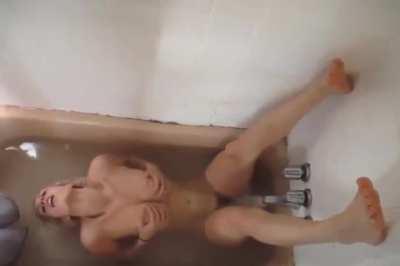 Nude in a bathtub with the faucet spraying her clit