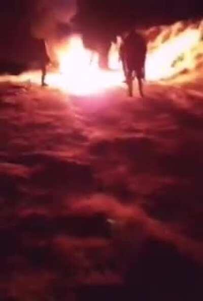 A group of Armenian soldiers are sitting around the fire, and one of them walks up to the group of Azeri soldiers.