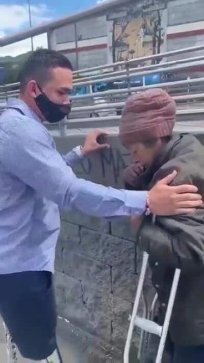 Double amputee with prosthetics gives his crutches to a homeless amputee