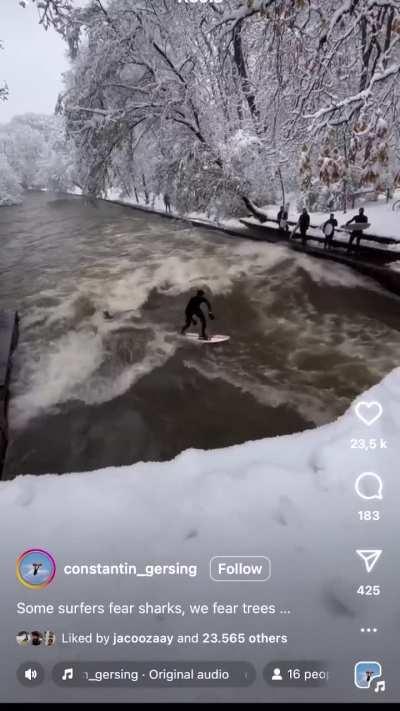 Tree falls as people surf the Eisbach in Munich during heavy snowstorm (02/12/23)