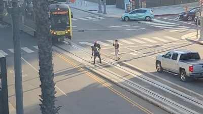 COMPASSION. A bystander hugs and pulls a distraught man off of train tracks in Long Beach.