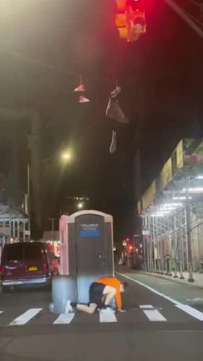 Using a porta potty to try to get some sneakers hanging from a wire