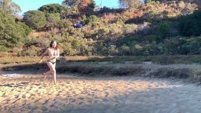 playing frisbee topless at a beach