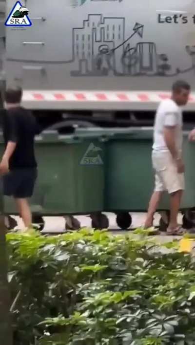 2 man puting another guy in the trash