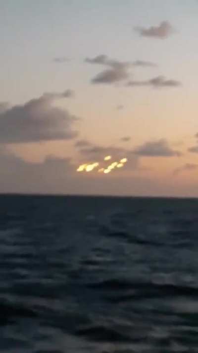 Video showing a cluster of 14 luminous orbs hovering in the sky over the middle of the ocean