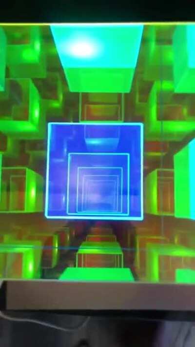 This is a Dichroic Infinity cube. Artist Sean Augustine March, from Binghamton, New York, created the mesmerising desktop 'lamp' using a combination of dichroic and reflective glass.