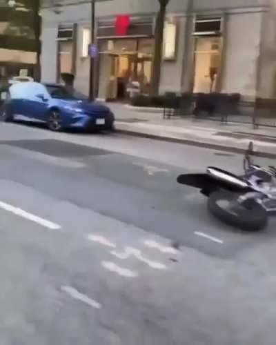 Slowing off a dirt bike on a street around parked cars.