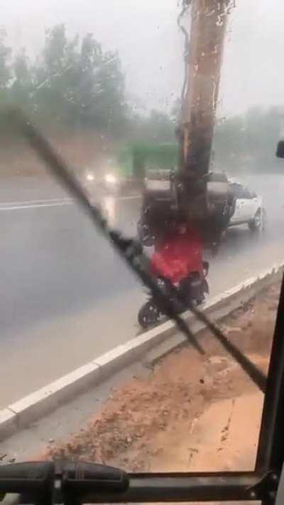 Backhoe operator helping this motorcyclist stay dry in the rain.