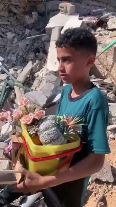 A child in Gaza Puts what's left of his childhood into a bucket after Israeli Airstrikes Leveled his home