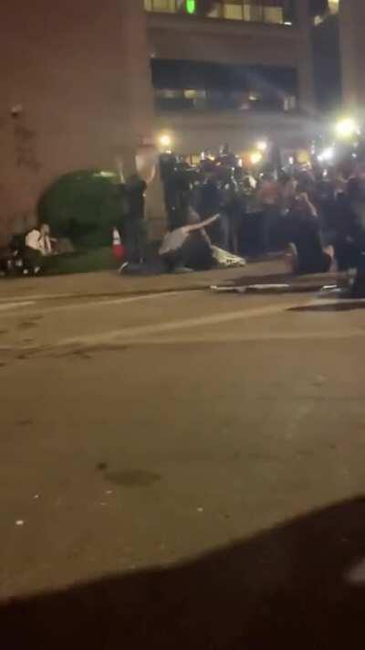 Protestors try to bring a man in critical condition to the cops for medical help, but the cops shoot at them.
