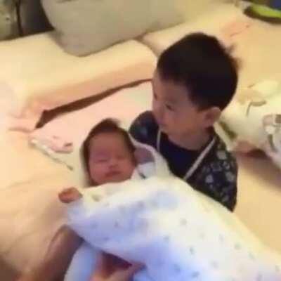 Mommy let big brother hold the baby for the first time.