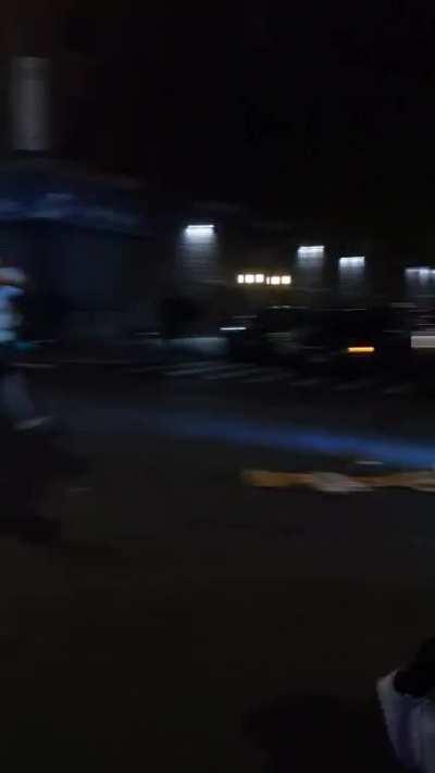 A minivan pulls up playing the Purge speech as crowd riots.