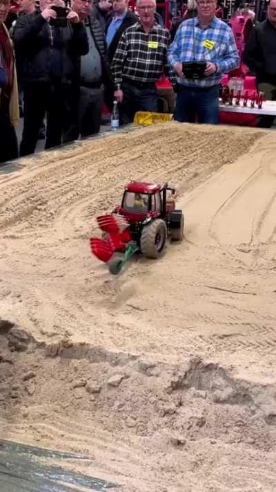 A remote control tractor tilling a small field.