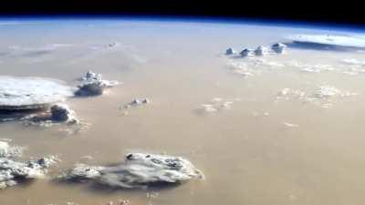 Earth looks like an alien world from the International Space Station with a massive sandstorm and towering cumulonimbus clouds covering the Sahara Desert. Credit: NASA