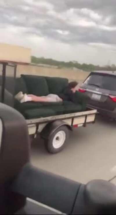 Idiot on sofa, on a trailer, while going on the highway