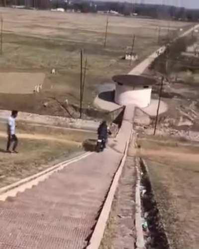 Biker goes down stairs wth the idea of jumping a building. Not so much