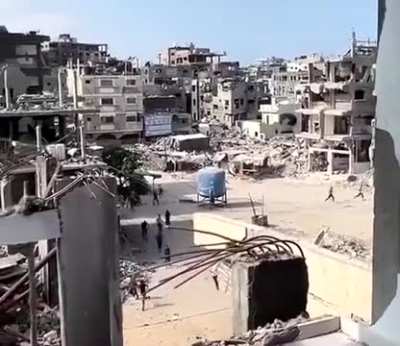 Group of people running away from a drone as it attempts to destroy a water container 