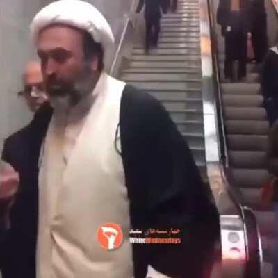 A cleric harassing a woman for not wearing a hijab properly.