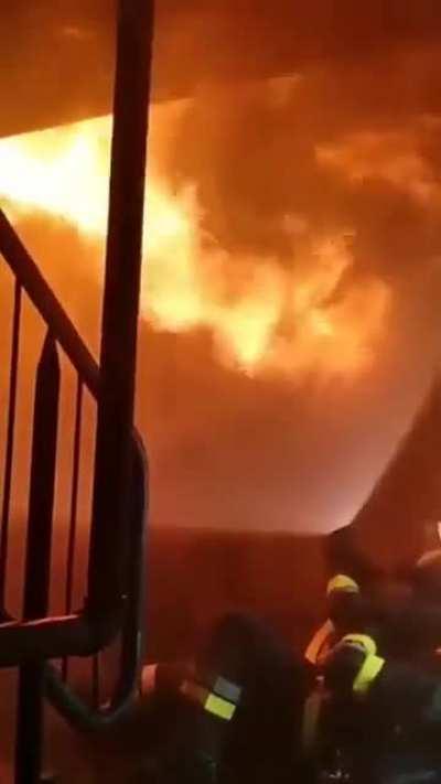 Firefighter uses water from hose to shield from the incoming flames from above.