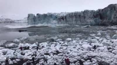 Tourists watch and scramble for cover as a huge chunk of the Breiðamerkurjökull glacier calves. The scale is hard to imagine until you see the waves.