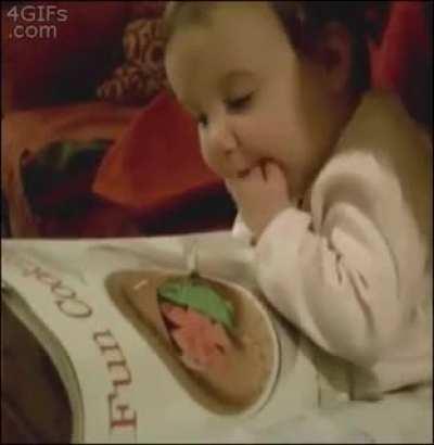 Baby eats food from a magazine