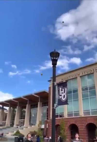 Dude throws an orange on a street lamp